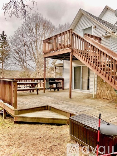 A deck with a hot tub and a staircase leading to a house.