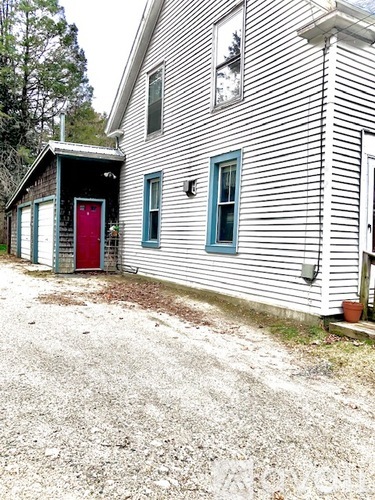 A white house with a red door and a small shed.