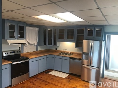A kitchen with wooden floors and a stainless steel refrigerator.