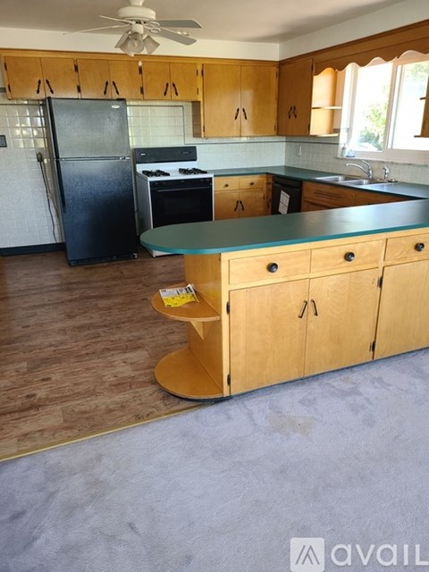 A kitchen with wooden cabinets and a black fridge.