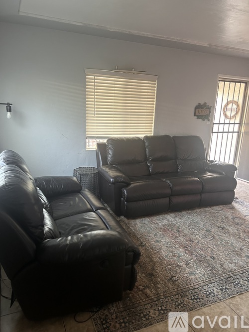Two black leather couches in a living room.