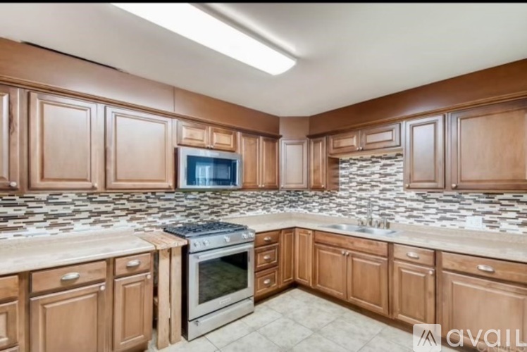 A kitchen with wooden cabinets and a stone backsplash.