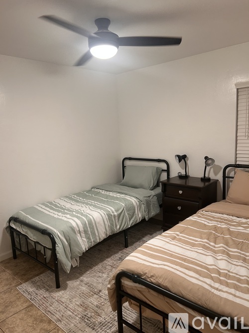 A bedroom with two beds and a ceiling fan.