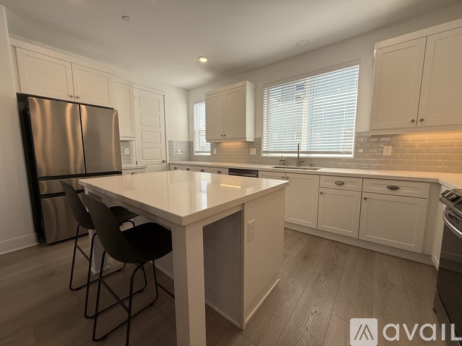 A kitchen with a white table and black chairs.