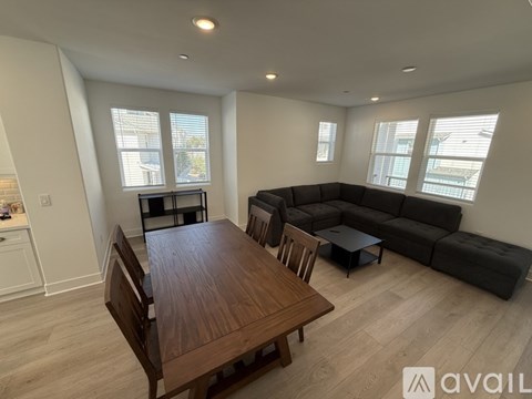 A living room with a wooden table and a black couch.