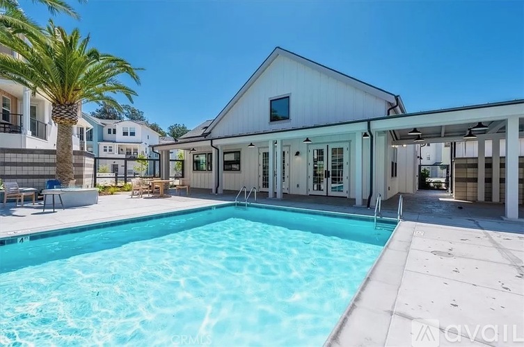 A swimming pool in front of a white building with a palm tree.