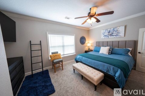 A bedroom with a blue bed and a ceiling fan.
