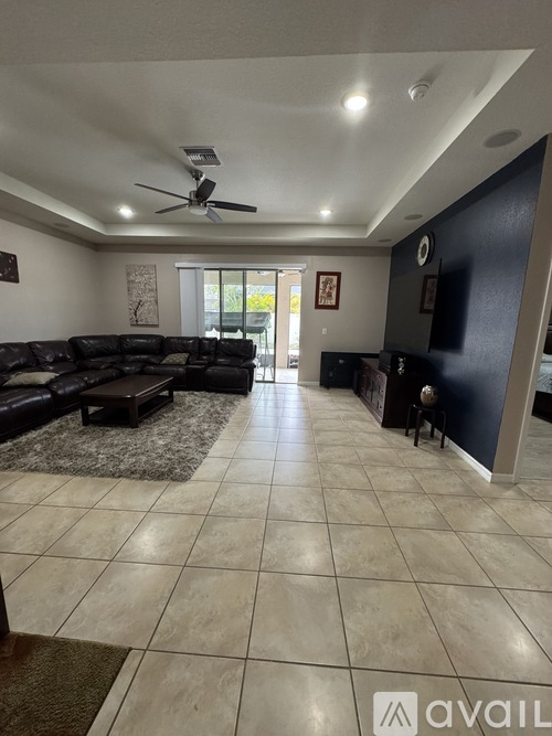 A spacious living room with a black couch and a rug.