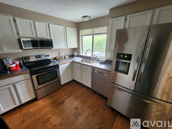 A kitchen with a stainless steel refrigerator and wooden floors.