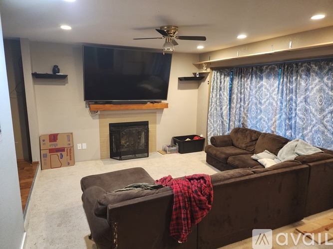 A living room with a fireplace and a television mounted above it.