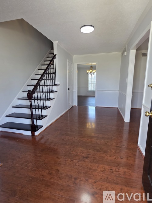 A hallway with a staircase and a chandelier.