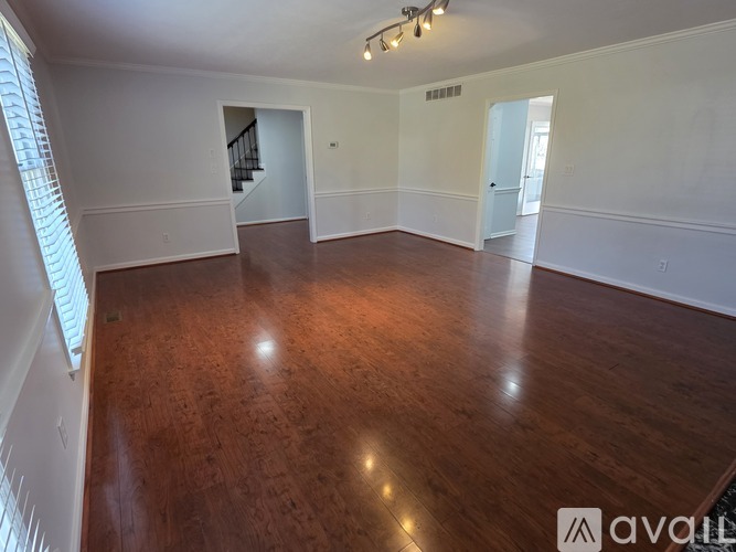 A spacious room with wooden flooring and white walls.