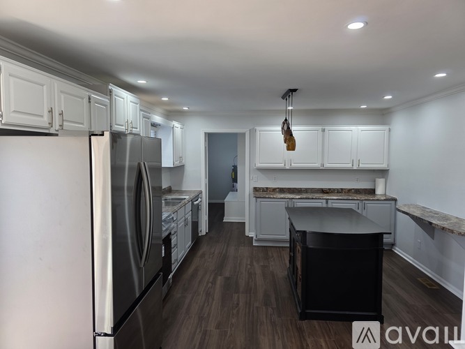 A kitchen with white cabinets and a black island.
