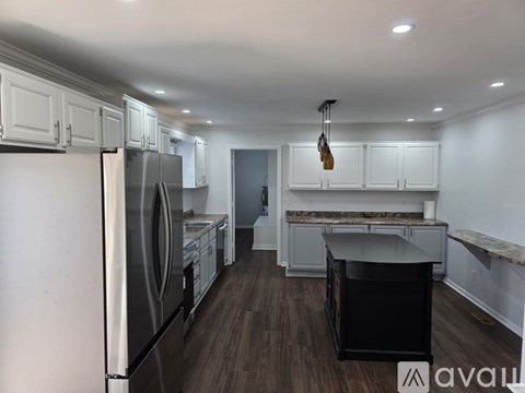 A kitchen with white cabinets and a black island.