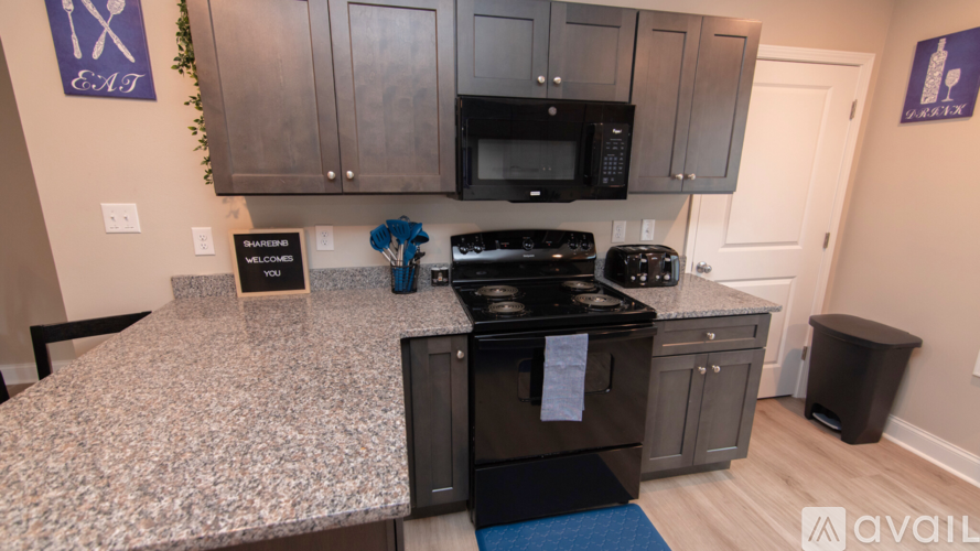 A kitchen with a granite countertop and a black stove top oven.