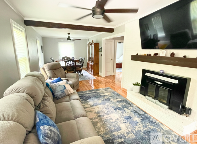 A living room with a fireplace and a television mounted above it.