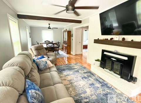 A living room with a fireplace and a television mounted above it.