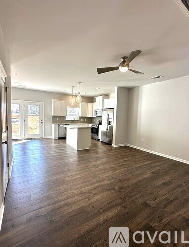A spacious room with wooden flooring and a ceiling fan.