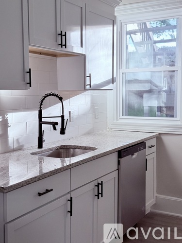 A kitchen with white cabinets and a black faucet.