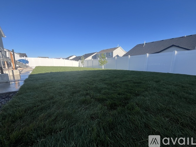 A grassy area with a white fence and houses in the background.
