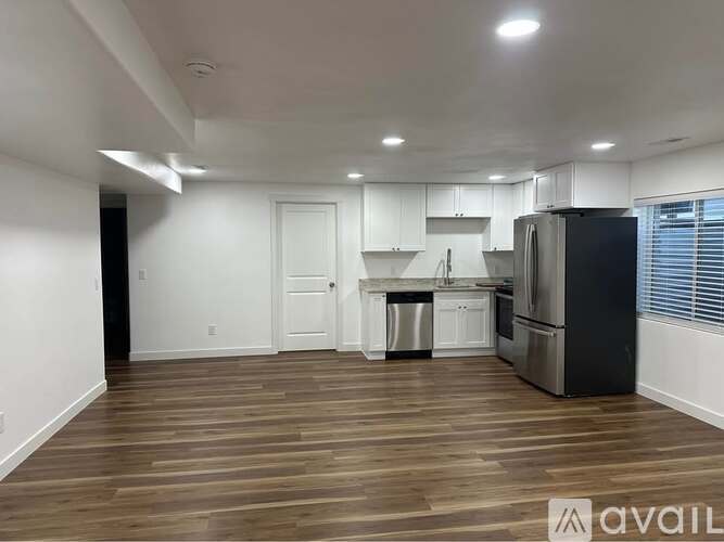 A kitchen area with a refrigerator, sink, and cabinets.