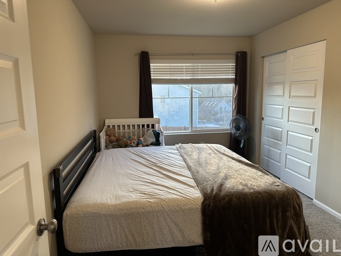 A bedroom with a large bed and a window with blinds.