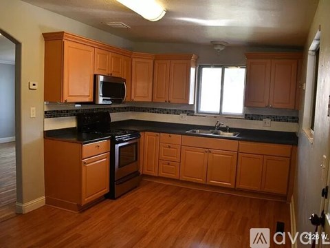 A kitchen with wooden cabinets and black countertops.