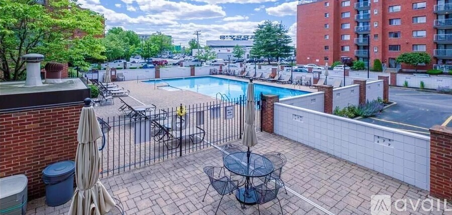 A patio with a table and chairs overlooks a pool.