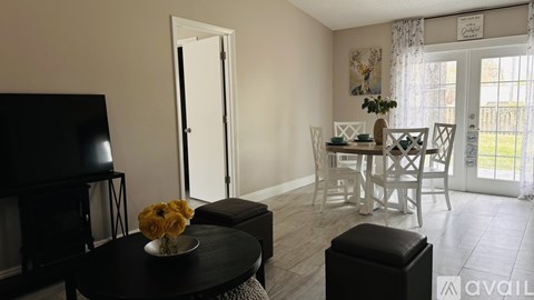 A living room with a black table and a white dining table.