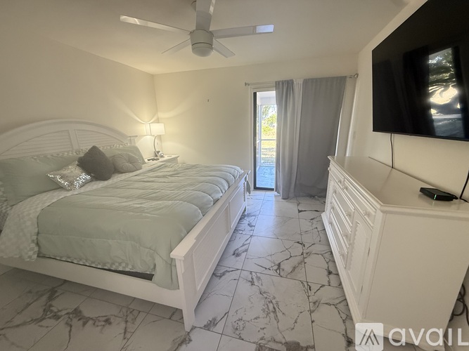 A bedroom with a large bed and a flat screen TV mounted on the wall.