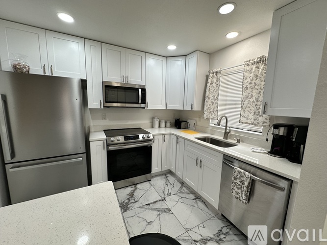 A kitchen with a marble countertop and stainless steel appliances.