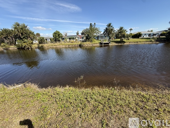 A body of water surrounded by greenery and buildings in the distance.