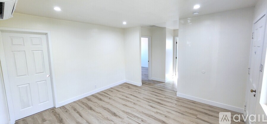 A spacious room with wooden flooring and white walls.