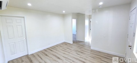 A spacious room with wooden flooring and white walls.