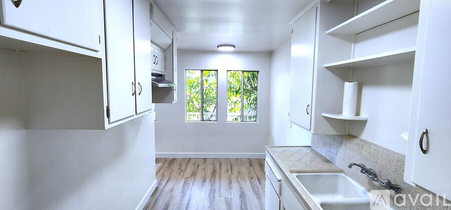 A kitchen with white cabinets and a window.