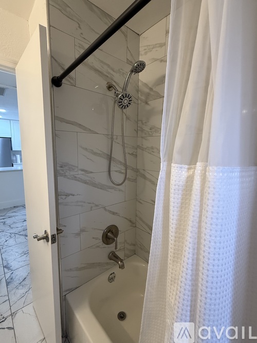 A bathroom with a white shower curtain and a marble tile shower.