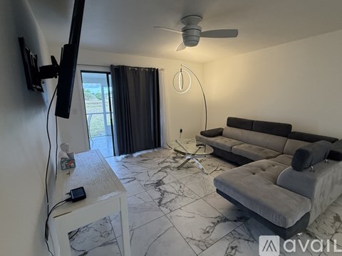A living room with a grey sofa and a television on the left side.