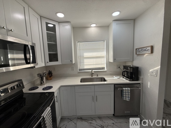 A kitchen with white cabinets and a black stove top.