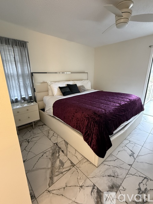 A bedroom with a bed, nightstand, and a ceiling fan.