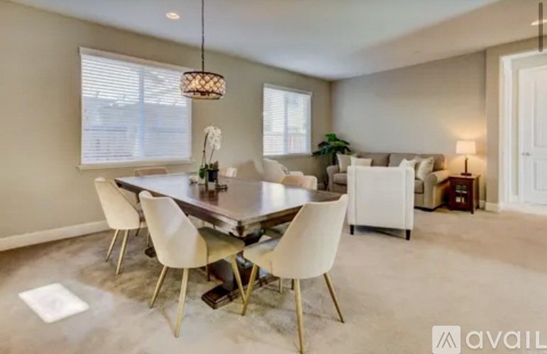 A modern dining room with a glass table and white chairs.