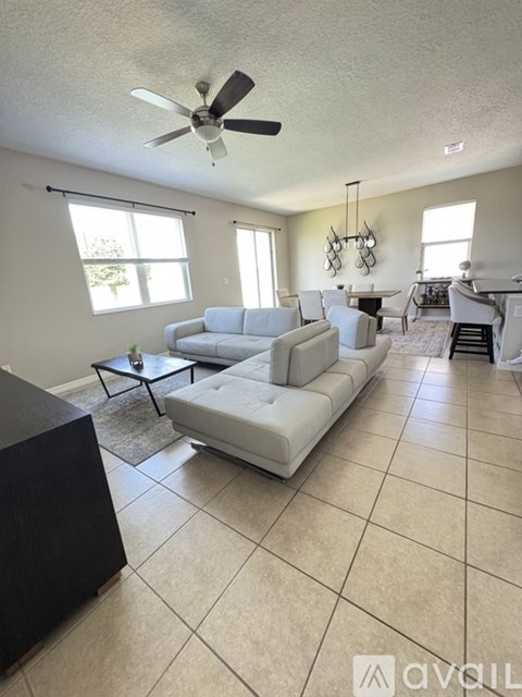 A living room with a white couch and a ceiling fan.