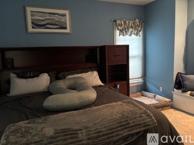 A bedroom with a bed, pillows, and a painting on the wall.