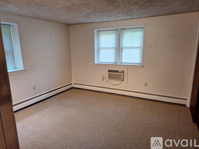 A room with a window and a carpeted floor.