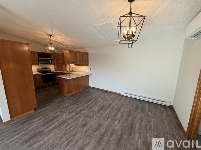A spacious living room with a kitchenette and a chandelier.