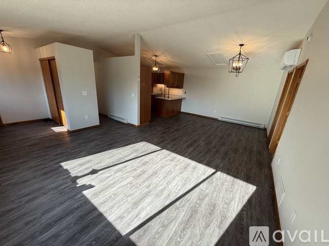 A spacious room with a large rug on the floor and wooden flooring.