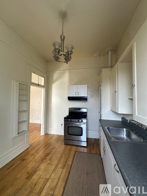 A kitchen with wooden floors and white cabinets.