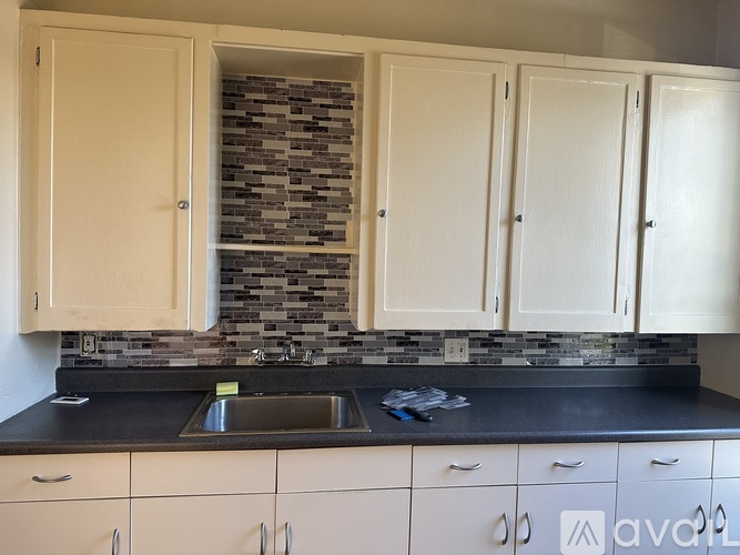 A kitchen with white cabinets and a black countertop.