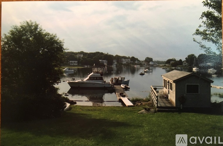 A serene lakeside scene with boats docked at a small pier and a house nearby.