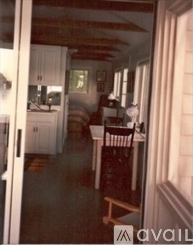 A kitchen with a table and chairs is visible through a glass door.