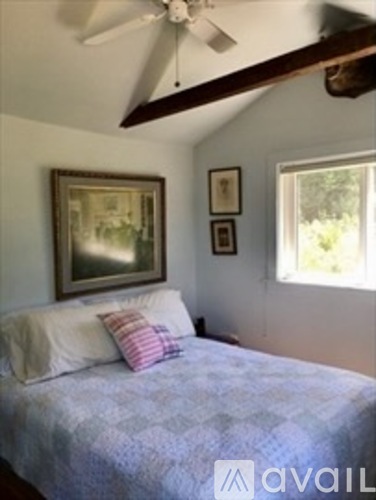 A bedroom with a bed, a ceiling fan, and pictures on the wall.